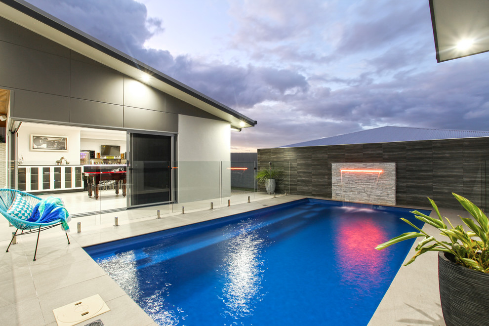 Inspiration for a mid-sized contemporary backyard rectangular pool in Other with a water feature and tile.