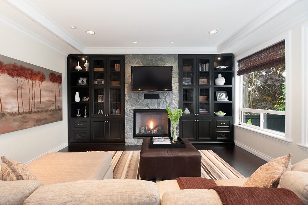 Traditional family room in Vancouver with a standard fireplace, a stone fireplace surround and a wall-mounted tv.
