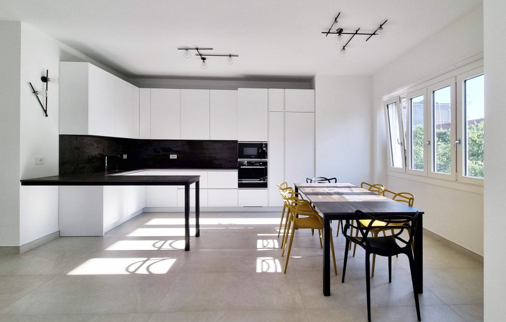 Design ideas for a large contemporary open plan kitchen in Milan with porcelain floors, an undermount sink, flat-panel cabinets, white cabinets, solid surface benchtops, stainless steel appliances, a peninsula and white floor.