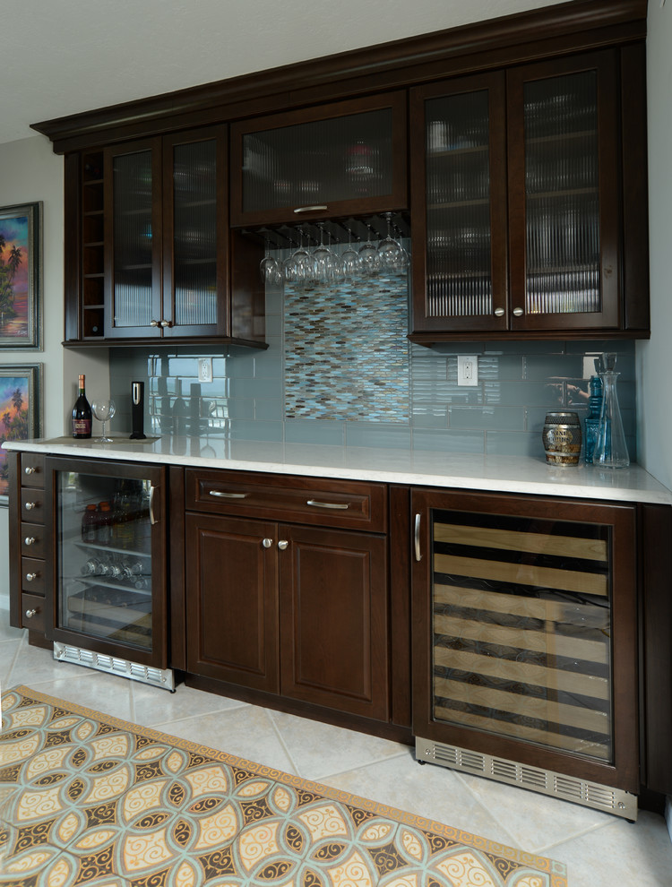 Design ideas for a large beach style single-wall wet bar in Orlando with raised-panel cabinets, dark wood cabinets, blue splashback and white floor.