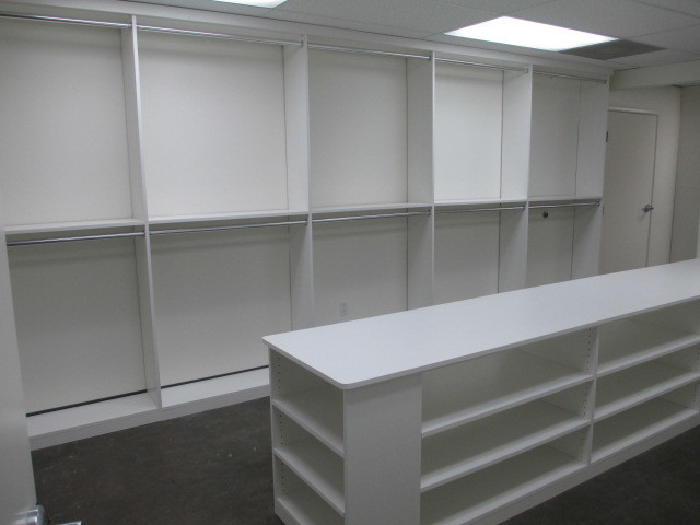This is an example of a large modern gender-neutral dressing room in Los Angeles with flat-panel cabinets, white cabinets, concrete floors and grey floor.