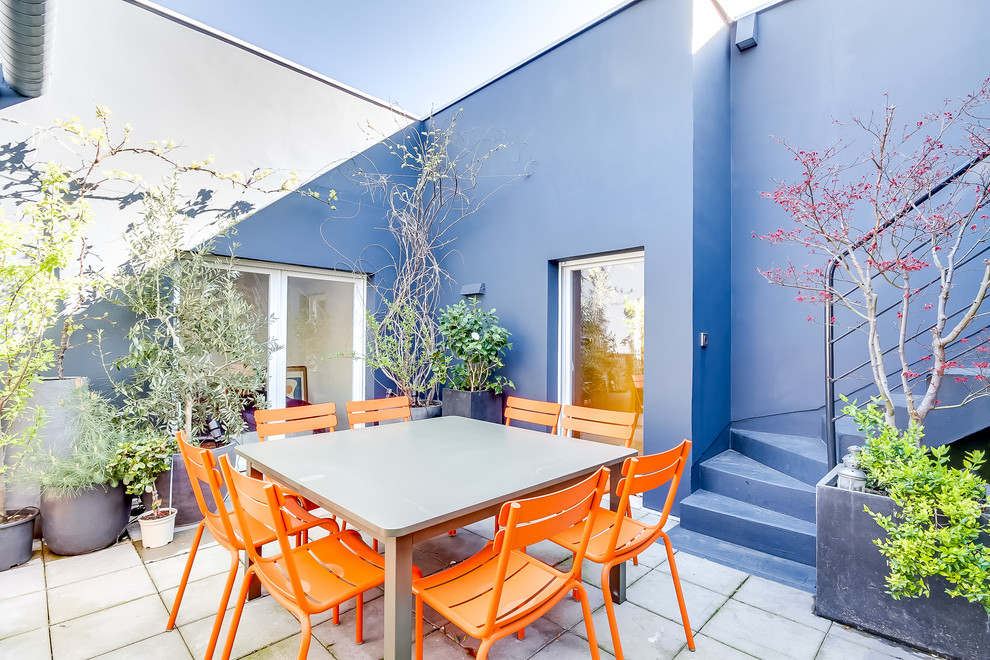 This is an example of a mid-sized contemporary courtyard patio in Paris with tile, no cover and a container garden.