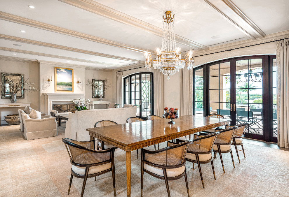 Expansive classic open plan dining room in Miami with dark hardwood flooring, a standard fireplace, a stone fireplace surround, brown floors, exposed beams, wallpapered walls and beige walls.