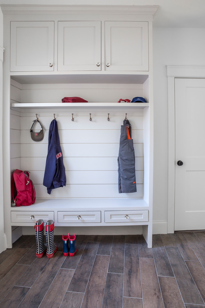 This is an example of a large beach style mudroom in Other with grey walls, porcelain floors, a single front door, a white front door and brown floor.