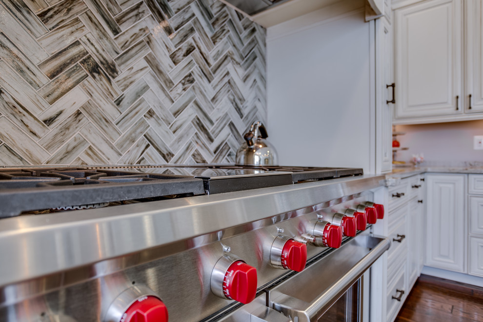 Example of a large u-shaped medium tone wood floor eat-in kitchen design in DC Metro with a drop-in sink, raised-panel cabinets, distressed cabinets, granite countertops, beige backsplash, glass tile backsplash, stainless steel appliances and two islands
