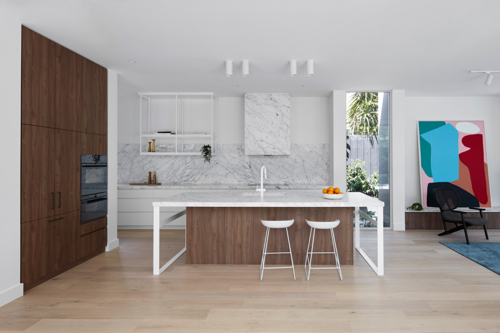 Moderne Küche mit Einbauwaschbecken, braunen Schränken, Quarzwerkstein-Arbeitsplatte, Küchenrückwand in Weiß, Rückwand aus Quarzwerkstein, hellem Holzboden, Kücheninsel, braunem Boden und weißer Arbeitsplatte in Melbourne
