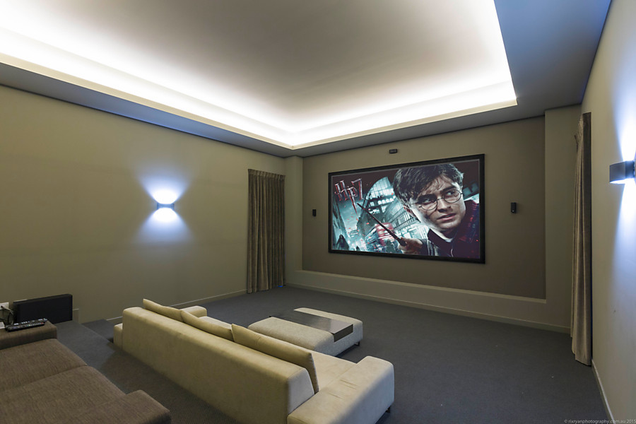 Photo of a large contemporary enclosed home theatre in Gold Coast - Tweed with brown walls, carpet and a projector screen.