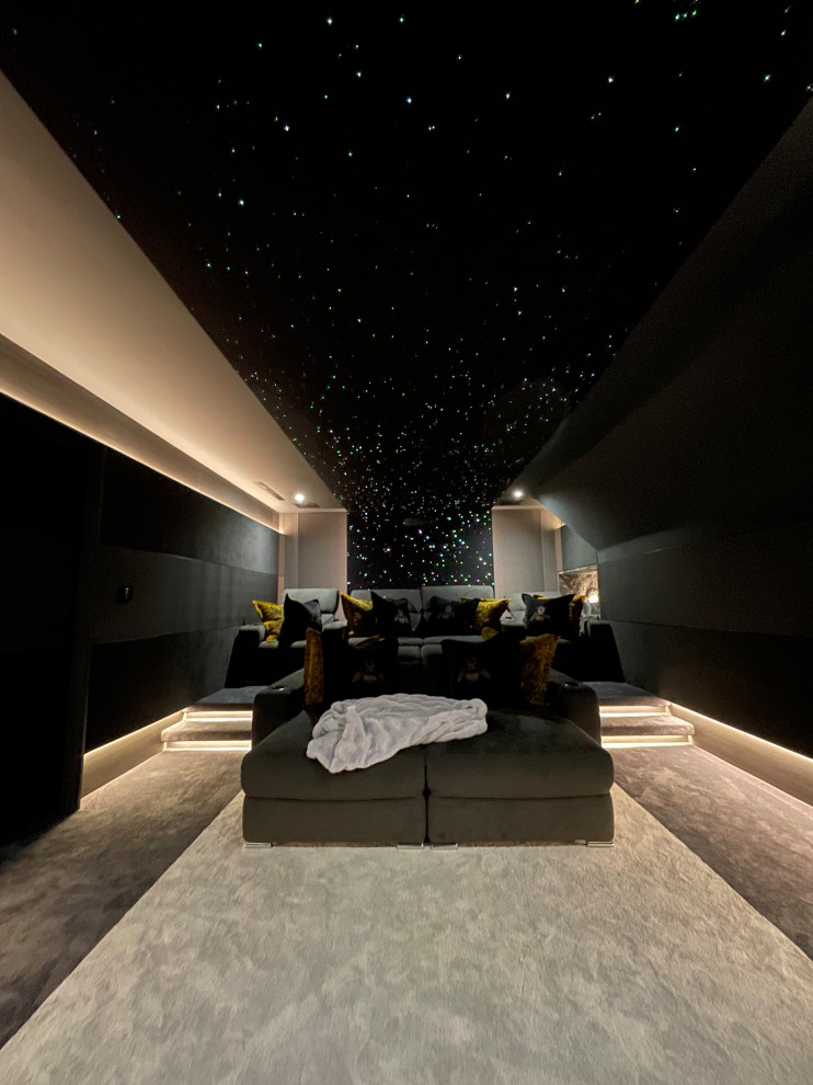 Mid-sized trendy carpeted and beige floor home theater photo in Hertfordshire with black walls and a projector screen