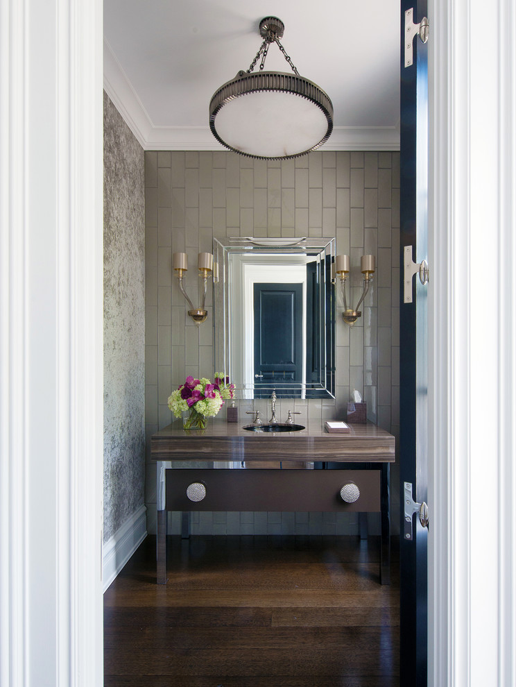 Photo of a transitional powder room in New York with furniture-like cabinets, gray tile, dark hardwood floors, an undermount sink and brown floor.