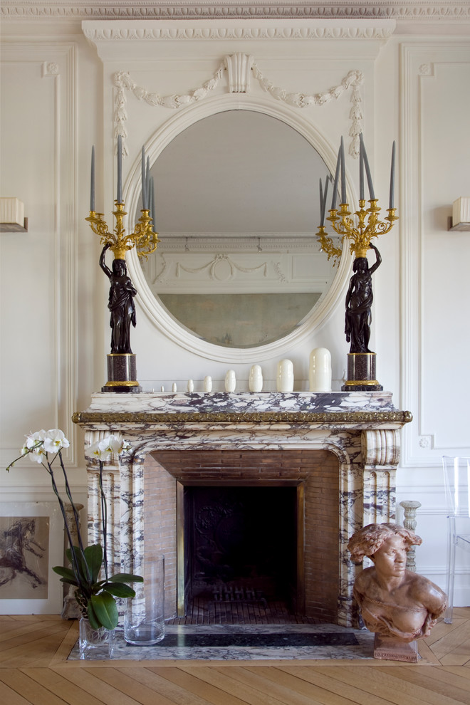 Photo of a large traditional enclosed living room in Paris with light hardwood flooring, a standard fireplace, a stone fireplace surround and no tv.