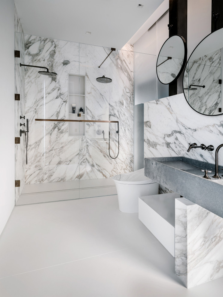 Design ideas for a contemporary master bathroom in Austin with flat-panel cabinets, grey cabinets, a curbless shower, a one-piece toilet, gray tile, white tile, marble, white walls, an integrated sink, white floor, a hinged shower door and grey benchtops.