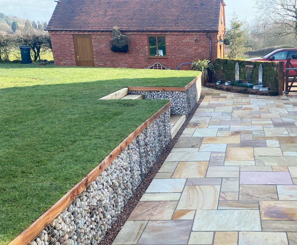 This is an example of a large country patio in Essex with natural stone pavers.