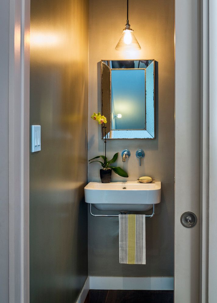 Photo of a contemporary powder room in New York with a wall-mount sink, grey walls and dark hardwood floors.