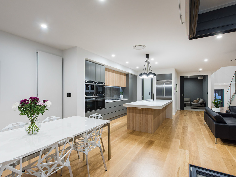 Inspiration for a mid-sized contemporary galley eat-in kitchen in Brisbane with an undermount sink, quartz benchtops, grey splashback, porcelain splashback, stainless steel appliances, light hardwood floors, with island, flat-panel cabinets and grey cabinets.
