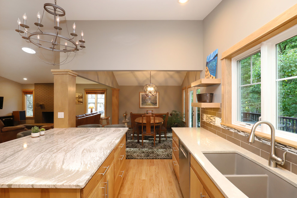 Eat-in kitchen - mid-sized transitional u-shaped light wood floor and brown floor eat-in kitchen idea in Grand Rapids with an undermount sink, flat-panel cabinets, light wood cabinets, quartz countertops, brown backsplash, ceramic backsplash, stainless steel appliances and an island