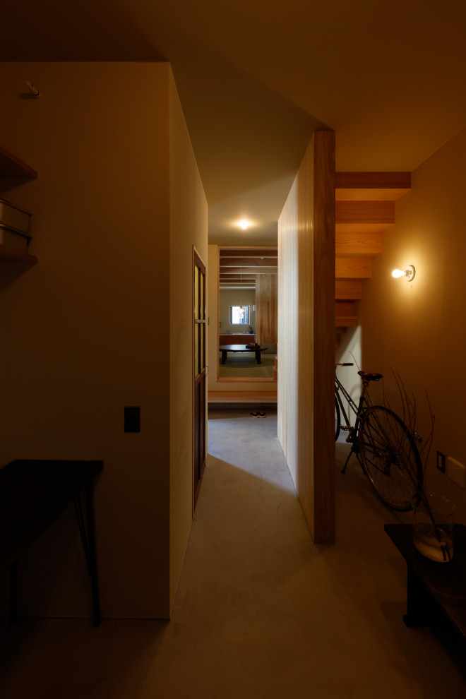 Photo of a small entry hall in Tokyo with yellow walls, concrete floors, a single front door, grey floor, wood and wood walls.