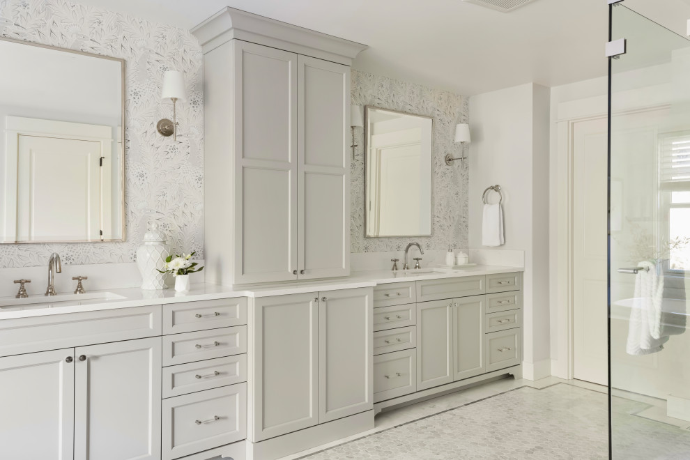 Источник вдохновения для домашнего уюта: большая главная ванная комната в стиле неоклассика (современная классика) с фасадами с утопленной филенкой, серыми фасадами, накладной ванной, двойным душем, раздельным унитазом, белой плиткой, мраморной плиткой, серыми стенами, мраморным полом, врезной раковиной, столешницей из искусственного кварца, белым полом, душем с распашными дверями, белой столешницей, сиденьем для душа, тумбой под две раковины, встроенной тумбой и обоями на стенах