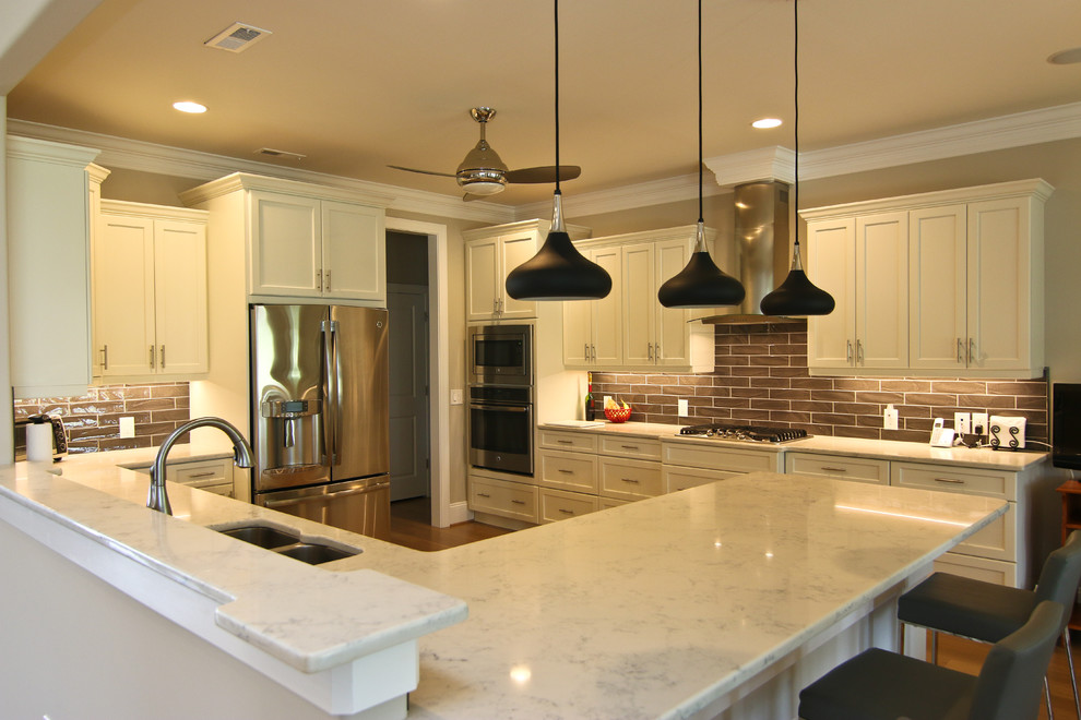 Large transitional u-shaped dark wood floor and brown floor eat-in kitchen photo in Wilmington with a double-bowl sink, recessed-panel cabinets, white cabinets, marble countertops, brown backsplash, subway tile backsplash, stainless steel appliances and a peninsula