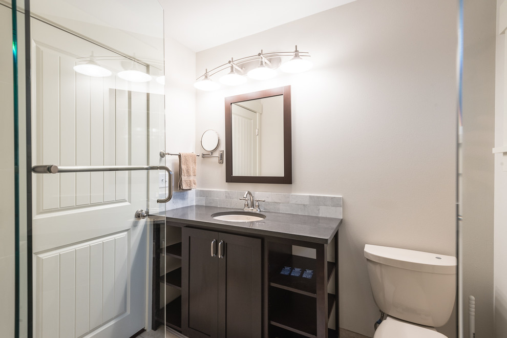 Inspiration for a mid-sized arts and crafts 3/4 bathroom in Seattle with shaker cabinets, dark wood cabinets, a two-piece toilet, multi-coloured tile, porcelain tile, white walls, porcelain floors, an undermount sink and engineered quartz benchtops.