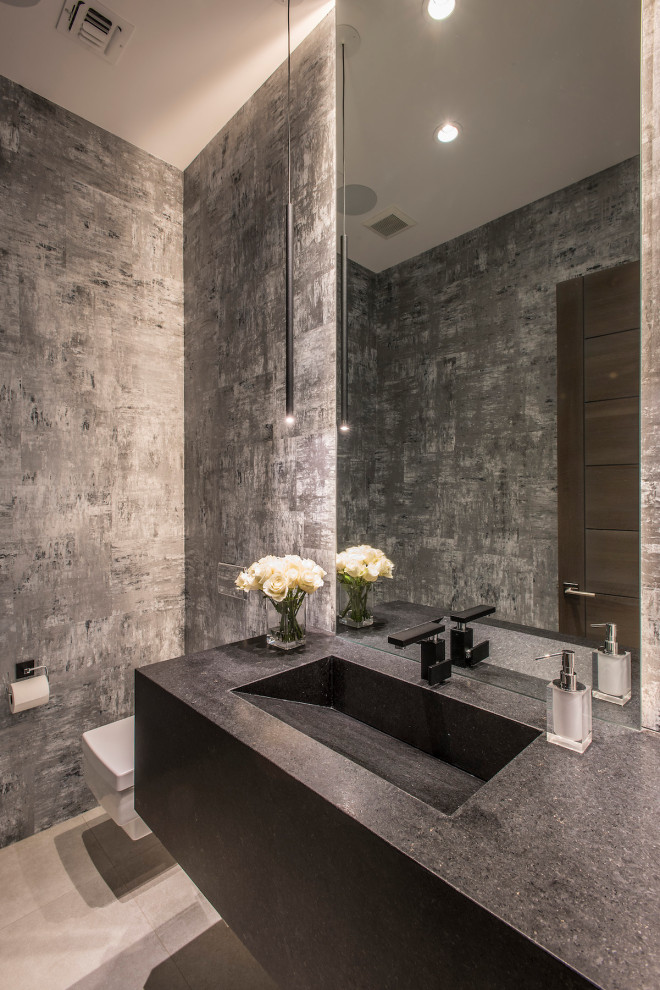 Inspiration for a large contemporary powder room in Phoenix with flat-panel cabinets, black cabinets, a wall-mount toilet, gray tile, porcelain floors, an integrated sink, grey floor, black benchtops and a floating vanity.
