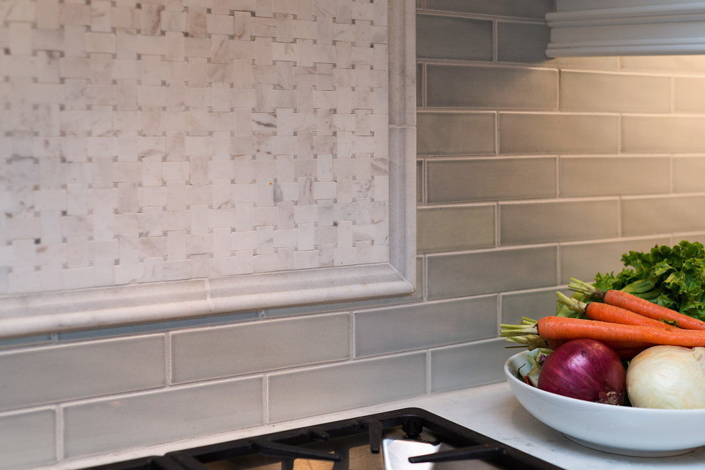 Example of a huge transitional l-shaped medium tone wood floor home design design with flat-panel cabinets, white cabinets, marble countertops, gray backsplash, porcelain backsplash, paneled appliances and an island