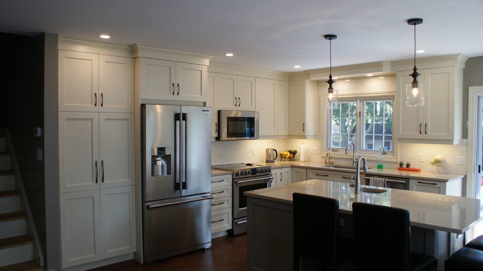 Example of a large transitional l-shaped eat-in kitchen design in Toronto with an undermount sink, shaker cabinets, white cabinets, quartz countertops, white backsplash, subway tile backsplash, stainless steel appliances and an island