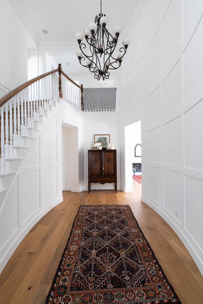 Idee per un ingresso tradizionale di medie dimensioni con pareti bianche, pavimento in legno massello medio, pavimento marrone e pannellatura