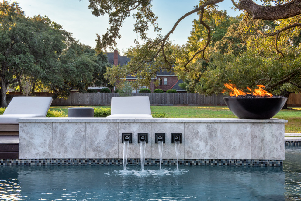 Large traditional backyard rectangular pool in Houston with natural stone pavers.