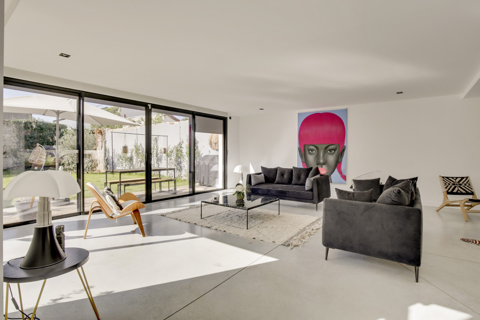 Photo of a contemporary open concept living room in Paris with white walls, concrete floors and grey floor.