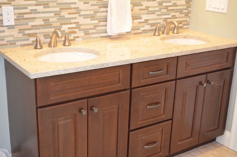 This is an example of a mid-sized transitional bathroom in Boston with an undermount sink, raised-panel cabinets, medium wood cabinets, engineered quartz benchtops, a shower/bathtub combo, porcelain floors, matchstick tile, grey walls, brown floor, a two-piece toilet, multi-coloured tile and a shower curtain.