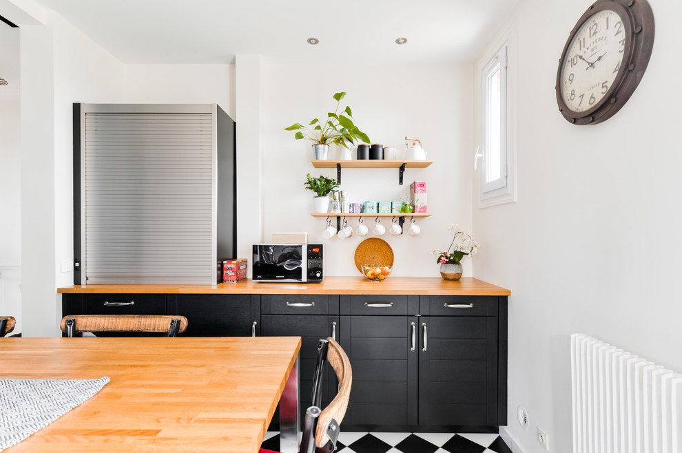 Inspiration for a mid-sized industrial galley separate kitchen in Paris with a double-bowl sink, shaker cabinets, black cabinets, wood benchtops, white splashback, subway tile splashback, stainless steel appliances, a peninsula, ceramic floors, black floor and brown benchtop.