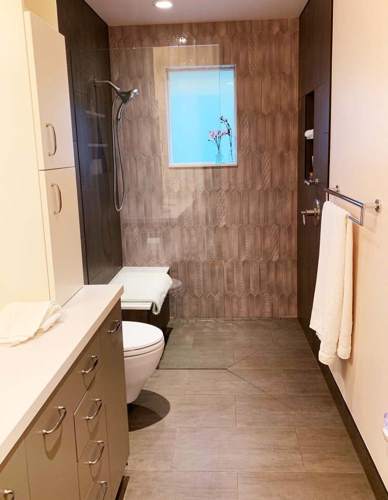 This is an example of a small contemporary 3/4 bathroom in Seattle with flat-panel cabinets, brown cabinets, a curbless shower, a wall-mount toilet, multi-coloured tile, porcelain tile, pink walls, porcelain floors, an undermount sink, engineered quartz benchtops, grey floor, an open shower and white benchtops.