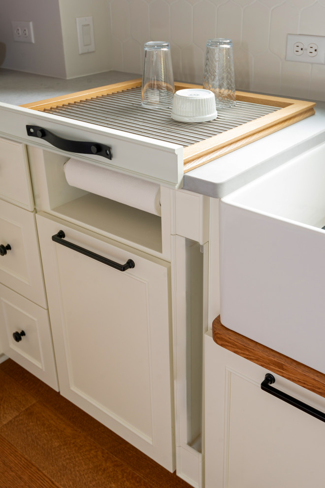Example of a large medium tone wood floor and exposed beam eat-in kitchen design with white backsplash, stainless steel appliances and an island