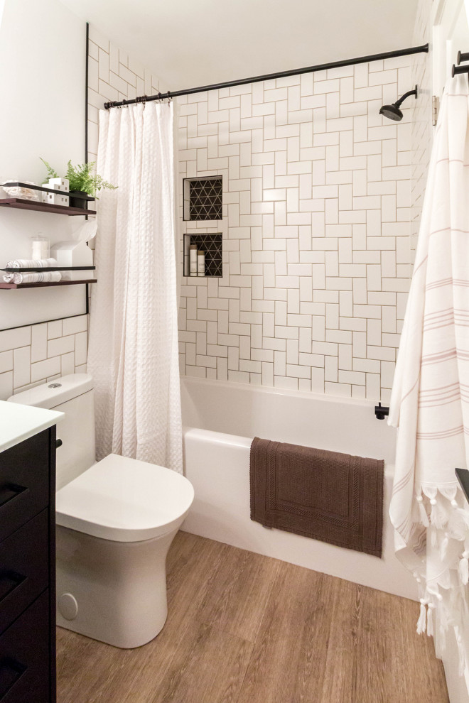 На фото: маленькая ванная комната в стиле модернизм с фасадами в стиле шейкер, черными фасадами, ванной в нише, душем над ванной, унитазом-моноблоком, белой плиткой, керамической плиткой, белыми стенами, полом из винила, врезной раковиной, столешницей из искусственного камня, коричневым полом, шторкой для ванной, белой столешницей, нишей, тумбой под одну раковину, напольной тумбой и панелями на стенах для на участке и в саду