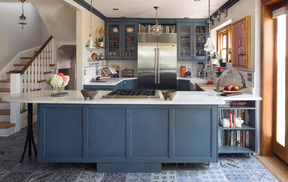 Mid-sized transitional ceramic tile and blue floor open concept kitchen photo in Denver with a farmhouse sink, glass-front cabinets, blue cabinets, marble countertops, white backsplash, ceramic backsplash, stainless steel appliances and white countertops