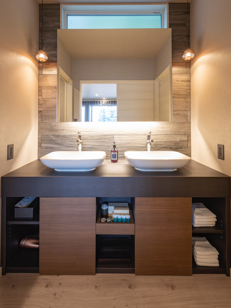 This is an example of a small modern powder room in Other with beaded inset cabinets, brown cabinets, a one-piece toilet, gray tile, porcelain tile, grey walls, plywood floors, a vessel sink, white benchtops and grey floor.