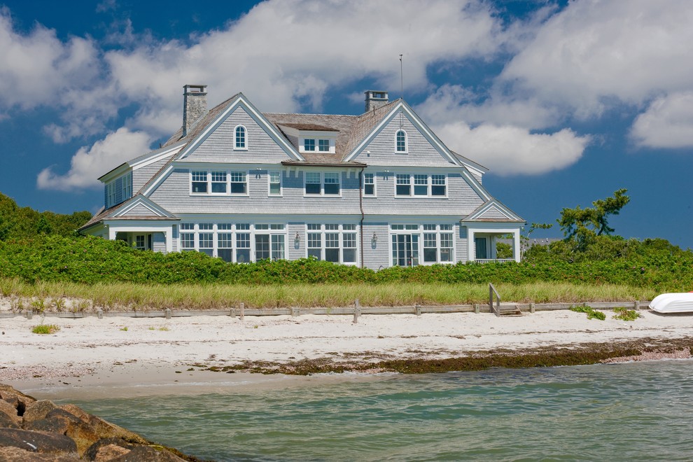 This is an example of a large beach style three-storey beige exterior in Boston with wood siding and a gable roof.