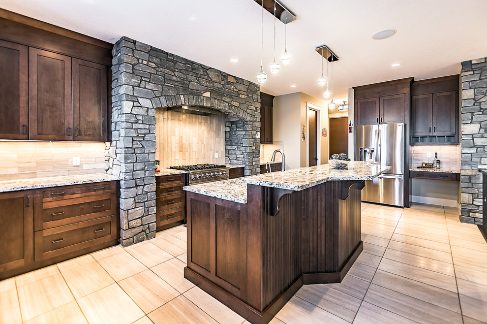 Large arts and crafts l-shaped eat-in kitchen in Calgary with an undermount sink, shaker cabinets, dark wood cabinets, granite benchtops, grey splashback, marble splashback, stainless steel appliances, light hardwood floors, with island and brown floor.