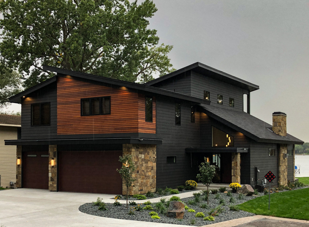 Стильный дизайн: большой, двухэтажный, черный частный загородный дом в современном стиле с комбинированной облицовкой, односкатной крышей, крышей из гибкой черепицы, черной крышей и отделкой планкеном - последний тренд