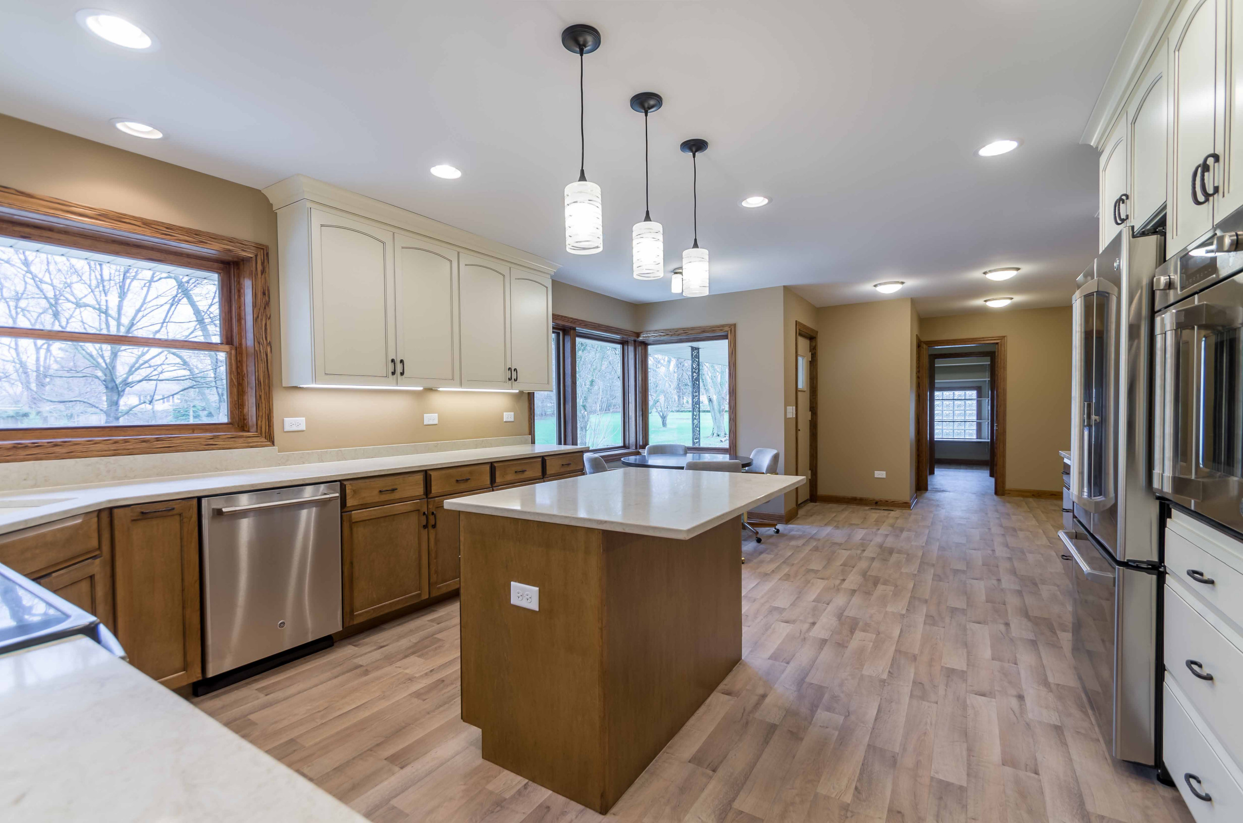 Example of a mid-sized classic l-shaped light wood floor, beige floor and wallpaper ceiling eat-in kitchen design in Chicago with recessed-panel cabinets, white cabinets, onyx countertops, white backs