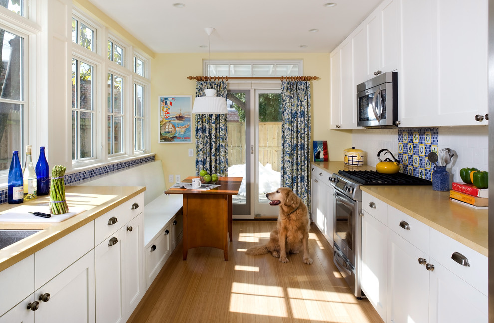 This is an example of a traditional galley separate kitchen in DC Metro with white cabinets, multi-coloured splashback, stainless steel appliances and shaker cabinets.