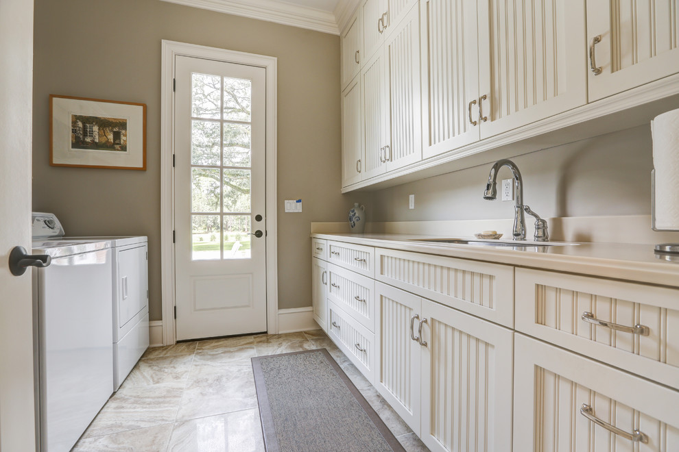 Mid-sized traditional galley dedicated laundry room in Jacksonville with an undermount sink, recessed-panel cabinets, white cabinets, solid surface benchtops, beige walls, ceramic floors and a side-by-side washer and dryer.