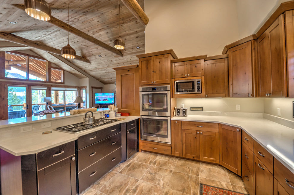 Design ideas for a mid-sized arts and crafts u-shaped open plan kitchen in Denver with shaker cabinets, light wood cabinets, quartz benchtops, stainless steel appliances, travertine floors and a peninsula.
