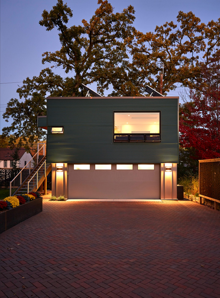 Cette image montre une petite façade de Tiny House métallique et verte design à un étage avec un toit plat.
