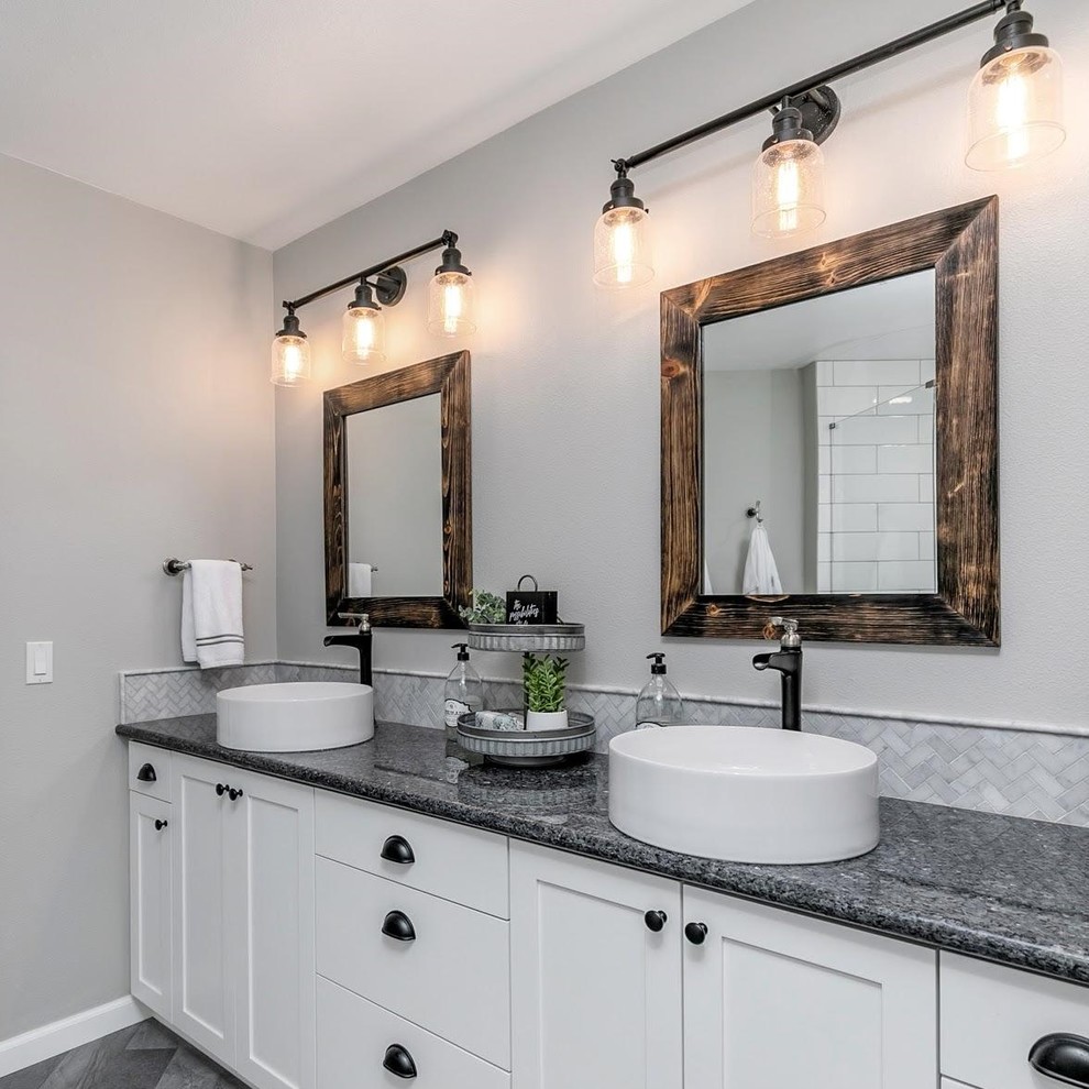 Design ideas for a large country master bathroom in Portland with shaker cabinets, white cabinets, a corner shower, a one-piece toilet, white tile, subway tile, grey walls, vinyl floors, a vessel sink, granite benchtops, grey floor, a hinged shower door and black benchtops.