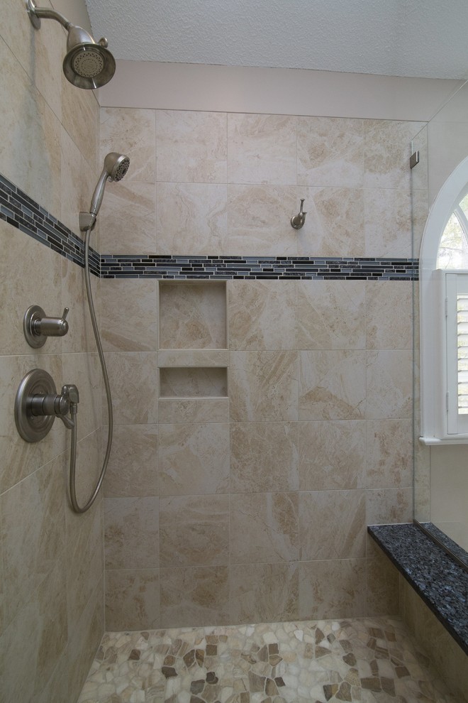 This is an example of a large transitional master bathroom in Raleigh with raised-panel cabinets, dark wood cabinets, a corner shower, a two-piece toilet, beige tile, porcelain tile, beige walls, porcelain floors, an undermount sink, granite benchtops, beige floor, a hinged shower door and blue benchtops.