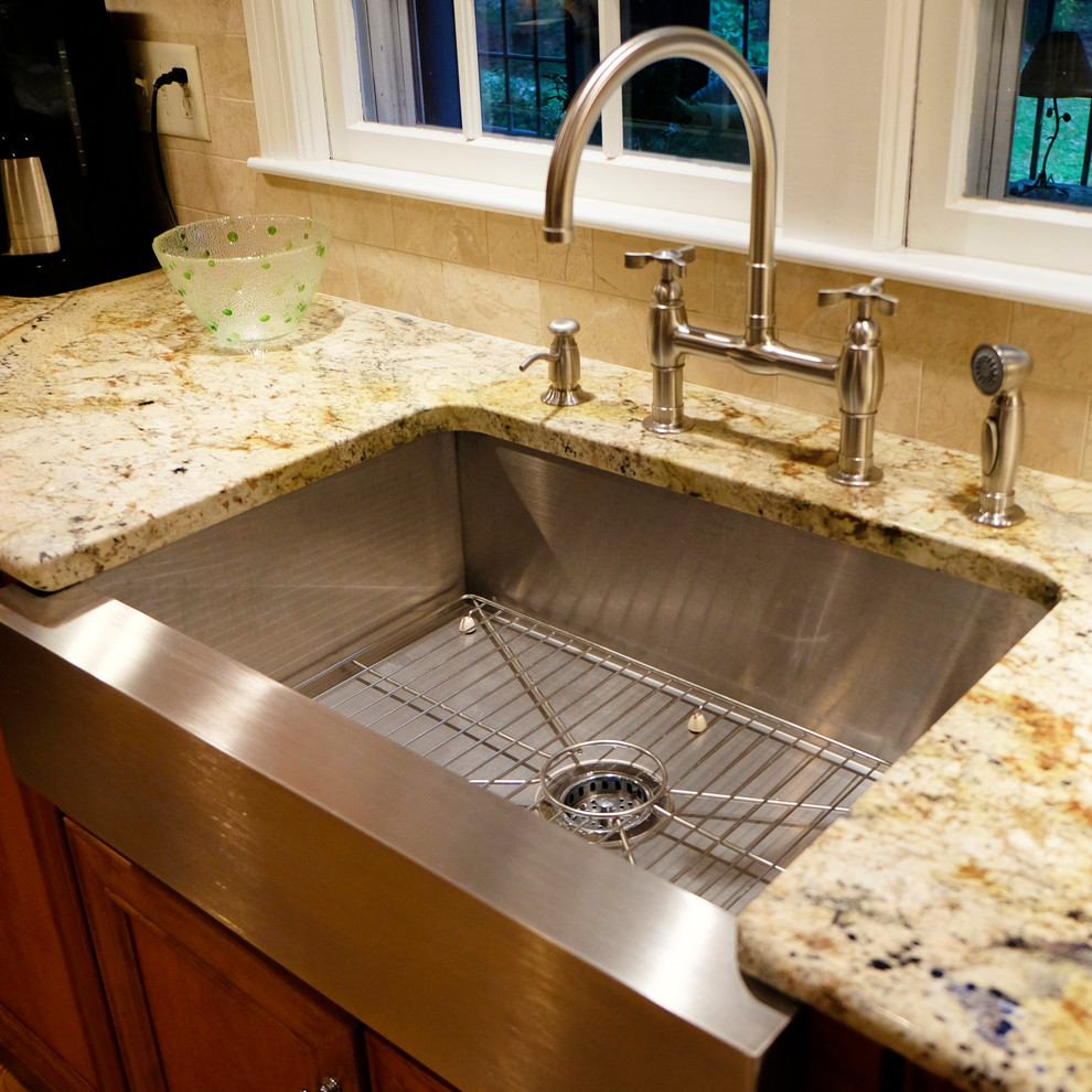 Eat-in kitchen - mid-sized transitional l-shaped medium tone wood floor eat-in kitchen idea in Boston with a farmhouse sink, flat-panel cabinets, medium tone wood cabinets, granite countertops, beige backsplash, subway tile backsplash, stainless steel appliances and an island