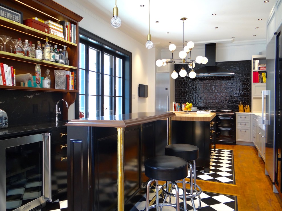 Small eclectic l-shaped eat-in kitchen in Calgary with a farmhouse sink, recessed-panel cabinets, marble benchtops, black splashback, ceramic splashback, stainless steel appliances, white cabinets, medium hardwood floors and with island.