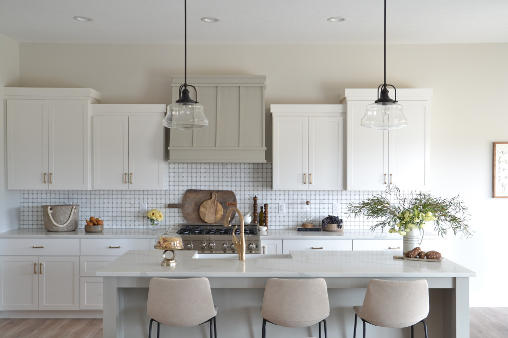 Design ideas for a transitional u-shaped eat-in kitchen in Indianapolis with a farmhouse sink, shaker cabinets, white cabinets, white splashback, stainless steel appliances, medium hardwood floors, with island and brown floor.