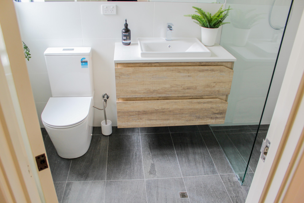 Inspiration for a small 3/4 bathroom in Perth with flat-panel cabinets, light wood cabinets, an open shower, a one-piece toilet, white tile, ceramic tile, white walls, porcelain floors, a vessel sink, engineered quartz benchtops, black floor and white benchtops.